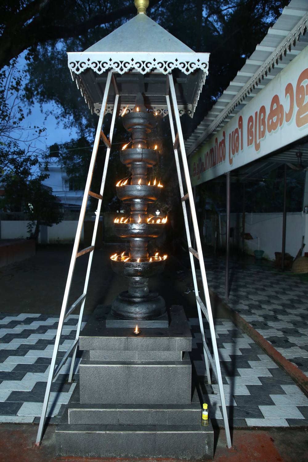 Nilavilakku lamp tower lit at dusk